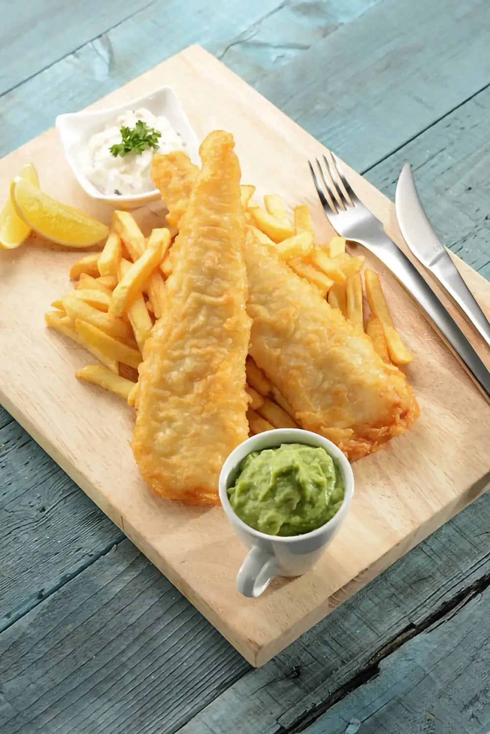 pacific west fish fillets cooked on pile of chips with tartare and mushy peas