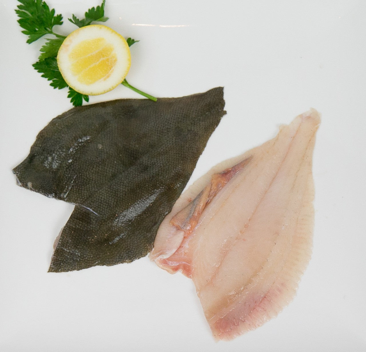 flounder fillets with lemon and parsley garnish on white plate