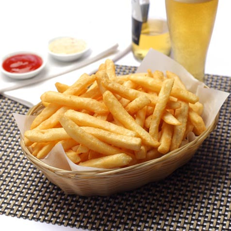 cooked fries in basket on women placement alongside beer and dipping sauces