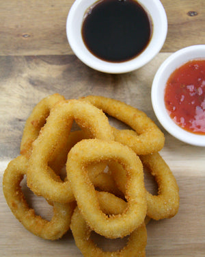 crumbed calamari pile on wooden plate with dipping sauces in bowls